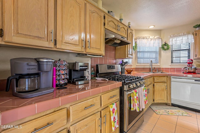 9769 Galilee Dr, El Paso, TX 79927 - kitchen featuring dishwasher, stainless steel gas range, under cabinet range hood, tile countertops, and a textured ceiling