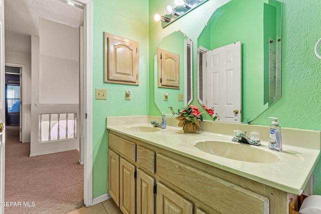 9769 Galilee Dr, El Paso, TX 79927 - bathroom featuring double vanity, a textured wall, and tile patterned flooring
