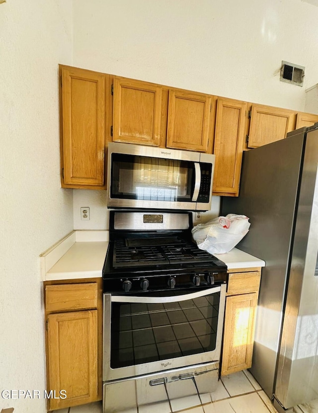 11049 Middledale St, El Paso, TX 79934 - kitchen featuring appliances with stainless steel finishes, light countertops, brown cabinets, and light tile patterned flooring