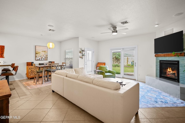11202 Redstone Peak Place, El Paso, TX 79934 - living area featuring light tile patterned floors, a glass covered fireplace, a ceiling fan, and a textured ceiling