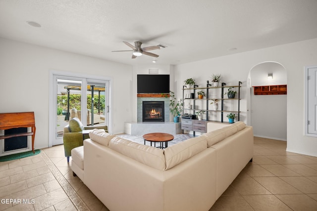 11202 Redstone Peak Place, El Paso, TX 79934 - living area featuring a glass covered fireplace, a ceiling fan, arched walkways, and light tile patterned floors