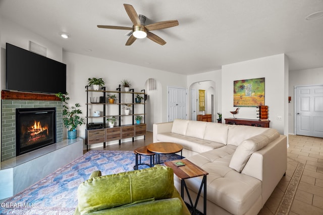 11202 Redstone Peak Place, El Paso, TX 79934 - living room with arched walkways, ceiling fan, a brick fireplace, and tile patterned floors