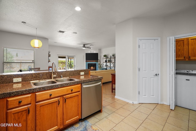 11202 Redstone Peak Place, El Paso, TX 79934 - kitchen featuring stainless steel dishwasher, washer / clothes dryer, tile counters, a warm lit fireplace, and ceiling fan