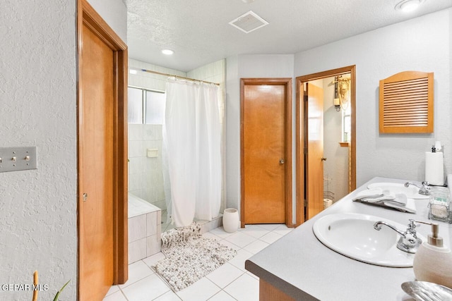 612 Firedale Ln, El Paso, TX 79912 - bathroom with a textured wall, a tile shower, double vanity, a textured ceiling, and tile patterned floors