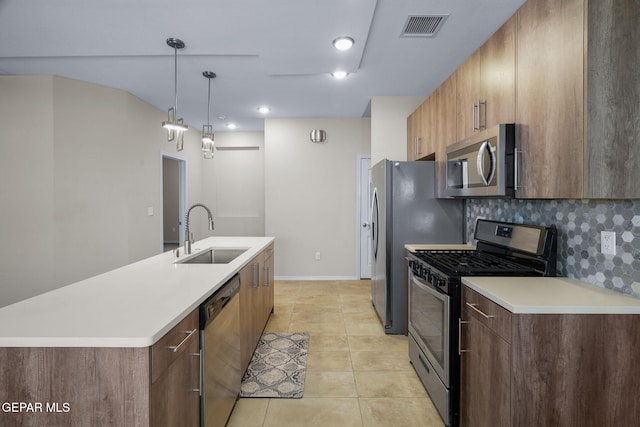 7722 Enchanted Ridge Dr, El Paso, TX 79911 - kitchen with stainless steel appliances, light countertops, a center island with sink, decorative backsplash, and pendant lighting