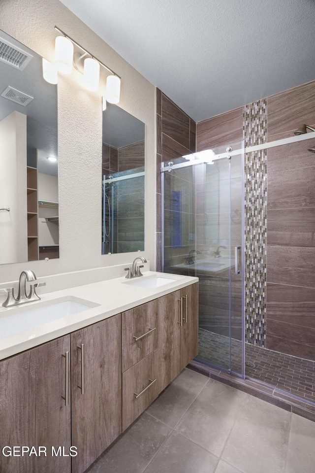 7722 Enchanted Ridge Dr, El Paso, TX 79911 - bathroom featuring double vanity, a shower stall, tile patterned flooring, and a textured ceiling