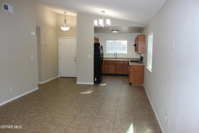 13978 Vaquero Rock Dr, El Paso, TX 79938 - kitchen with lofted ceiling, brown cabinetry, freestanding refrigerator, light countertops, and light tile patterned floors
