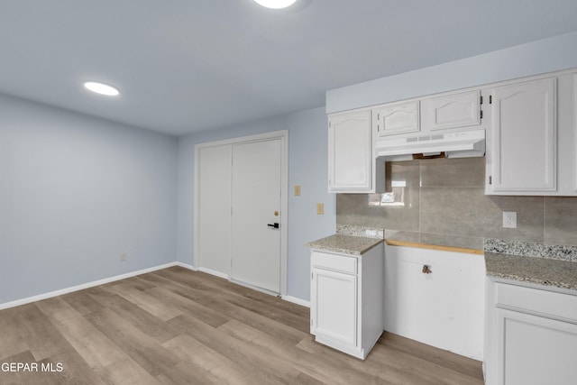 231 Romeria Dr, El Paso, TX 79907 - kitchen with under cabinet range hood, white cabinets, light wood-style flooring, decorative backsplash, and light stone counters