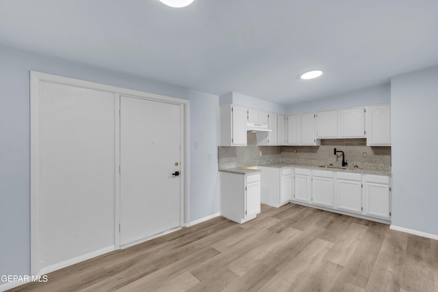231 Romeria Dr, El Paso, TX 79907 - kitchen with under cabinet range hood, light wood-style floors, white cabinets, and decorative backsplash