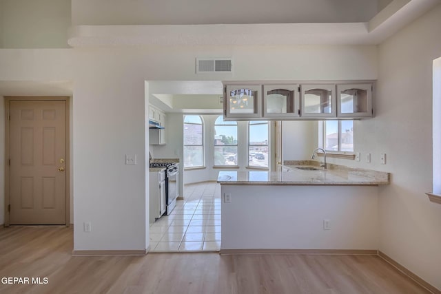 3148 Tierra Encino Dr, El Paso, TX 79938 - kitchen with stainless steel gas range, a peninsula, healthy amount of natural light, and light wood-style floors