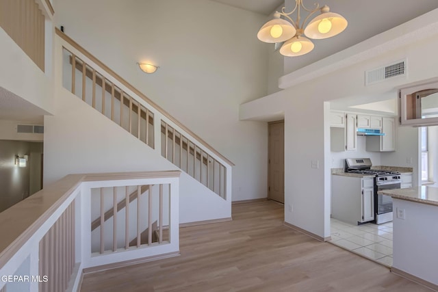 3148 Tierra Encino Dr, El Paso, TX 79938 - kitchen featuring gas stove, a high ceiling, under cabinet range hood, light countertops, and a chandelier