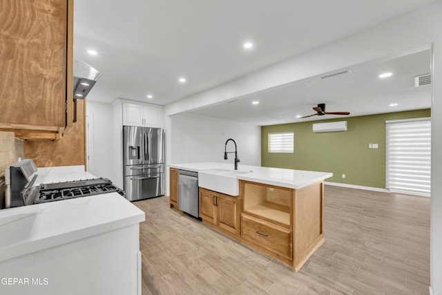 10229 Luella Ave, El Paso, TX 79925 - kitchen featuring stainless steel appliances, an AC wall unit, ceiling fan, range hood, and light wood-type flooring