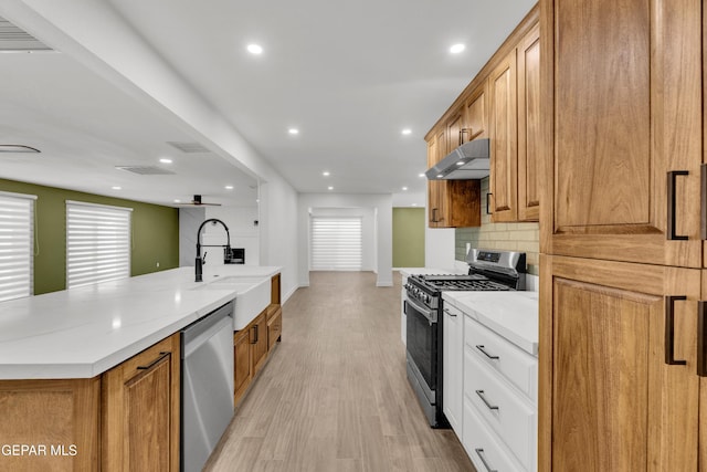 10229 Luella Ave, El Paso, TX 79925 - kitchen with stainless steel appliances, under cabinet range hood, decorative backsplash, a large island, and brown cabinetry