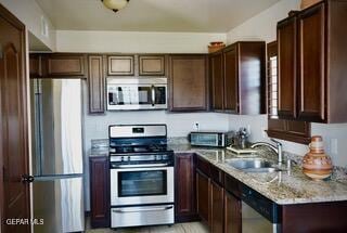13643 Pecos River Rd, Clint, TX 79836 - kitchen with stainless steel appliances, dark brown cabinets, and light stone countertops