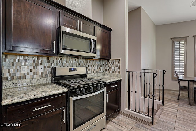 12511 Furlong Cir, El Paso, TX 79928 - kitchen featuring stainless steel appliances, decorative backsplash, dark brown cabinets, light stone countertops, and light wood finished floors