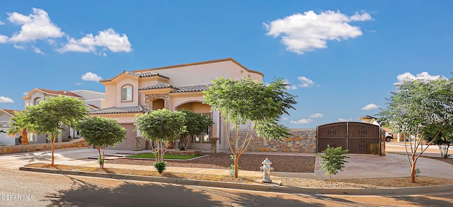 12511 Furlong Cir, El Paso, TX 79928 - mediterranean / spanish home with concrete driveway, a gate, stucco siding, a tile roof, and an attached garage