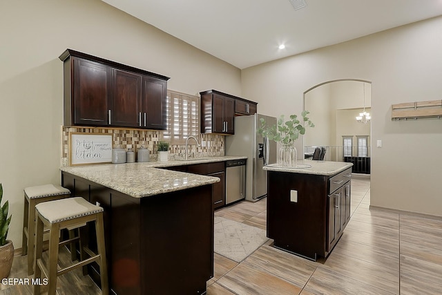 12511 Furlong Cir, El Paso, TX 79928 - kitchen featuring stainless steel appliances, dark brown cabinetry, decorative backsplash, a center island, and light stone counters