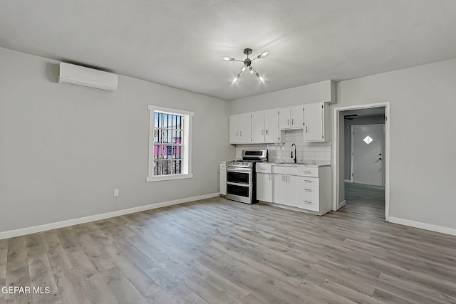 209 Hardesty Pl, El Paso, TX 79905 - kitchen with range with two ovens, an AC wall unit, light wood finished floors, tasteful backsplash, and white cabinetry