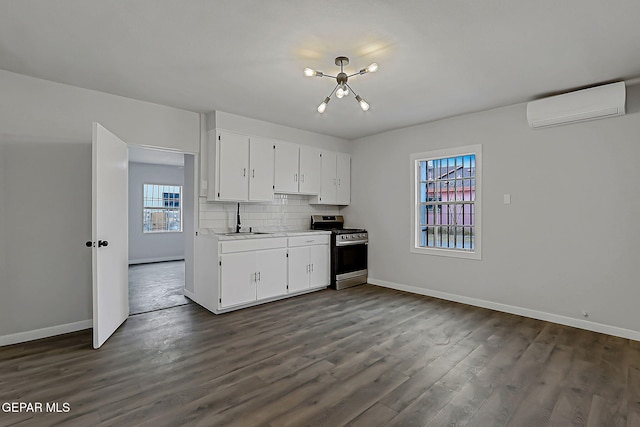 209 Hardesty Pl, El Paso, TX 79905 - kitchen featuring stainless steel gas range, an AC wall unit, dark wood-style flooring, and white cabinets