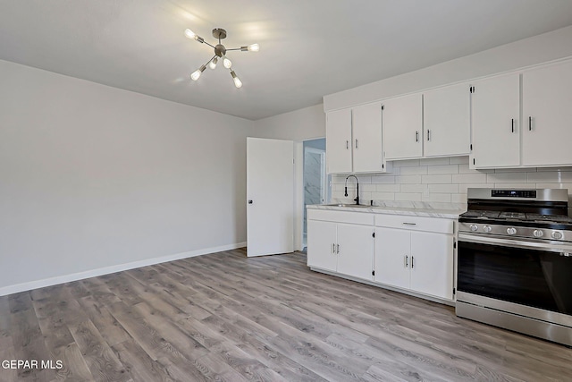 209 Hardesty Pl, El Paso, TX 79905 - kitchen featuring stainless steel gas range oven, light countertops, a chandelier, backsplash, and light wood-style flooring