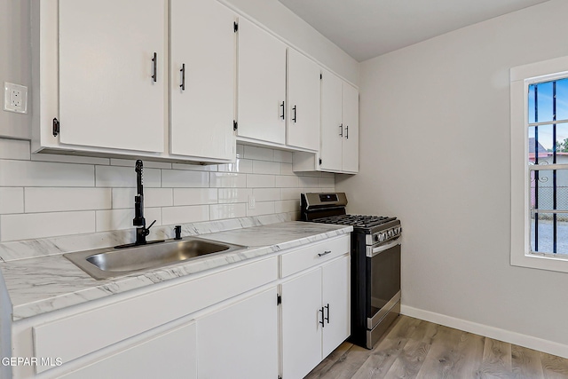 209 Hardesty Pl, El Paso, TX 79905 - kitchen featuring stainless steel gas range oven, decorative backsplash, light wood-style floors, and white cabinetry