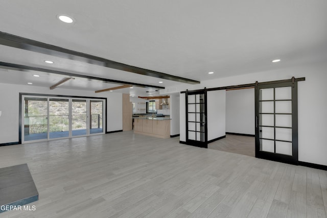 3116 Titanic Ave, El Paso, TX 79904 - unfurnished living room with a barn door, beam ceiling, light wood-style floors, and recessed lighting