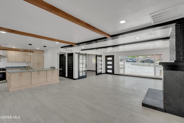 3116 Titanic Ave, El Paso, TX 79904 - kitchen featuring a barn door, beam ceiling, open floor plan, recessed lighting, and light wood-type flooring