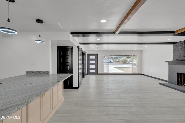 3116 Titanic Ave, El Paso, TX 79904 - kitchen with beam ceiling, light wood-style floors, a tile fireplace, open floor plan, and cream cabinetry