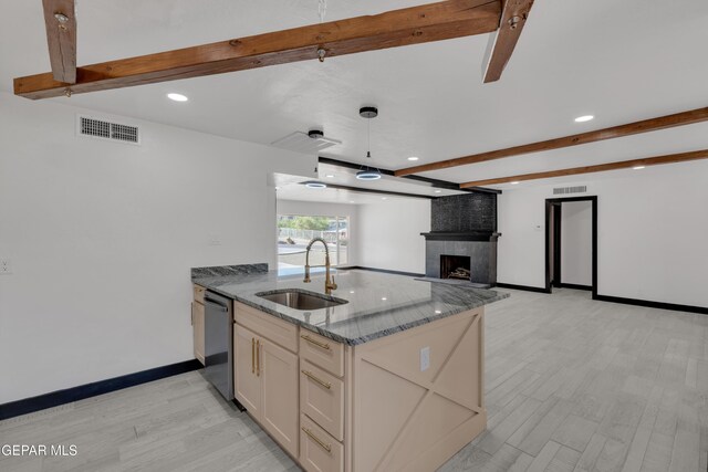 3116 Titanic Ave, El Paso, TX 79904 - kitchen featuring beam ceiling, dishwasher, light wood-type flooring, dark stone countertops, and a fireplace