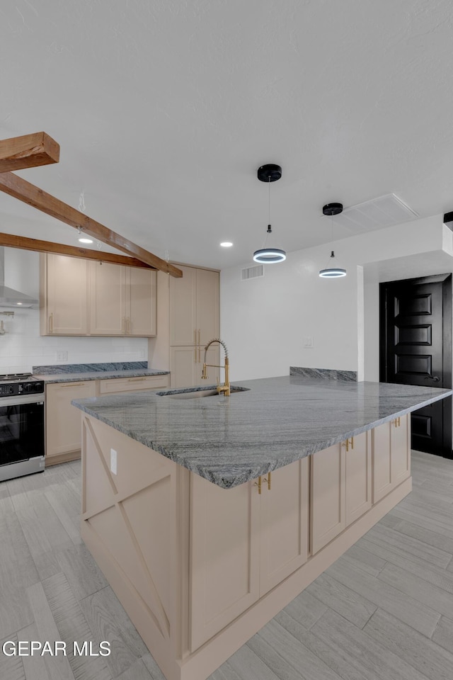 3116 Titanic Ave, El Paso, TX 79904 - kitchen featuring stainless steel range with gas stovetop, light stone counters, wall chimney range hood, pendant lighting, and cream cabinets