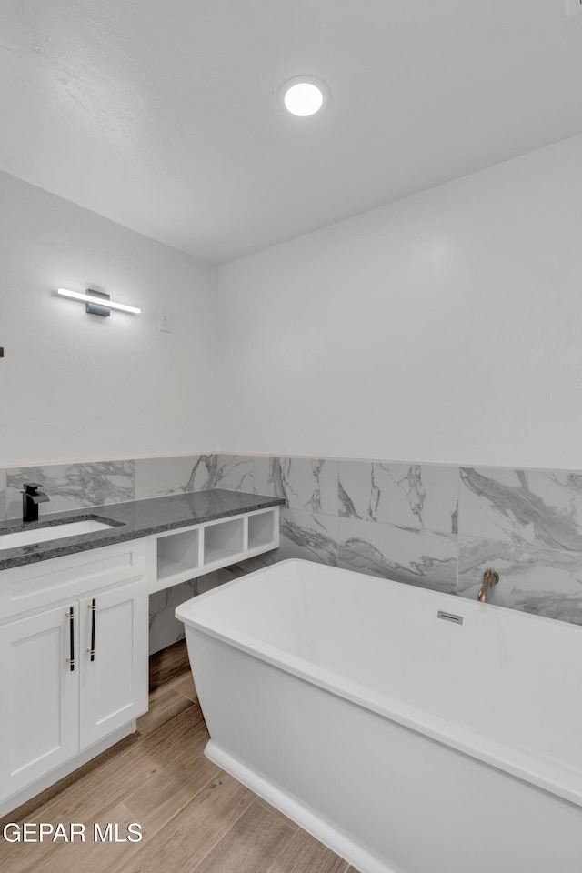 3116 Titanic Ave, El Paso, TX 79904 - full bath featuring a freestanding bath, vanity, wood finished floors, a wainscoted wall, and tile walls