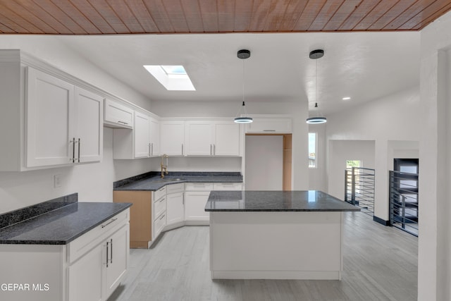 3116 Titanic Ave, El Paso, TX 79904 - kitchen with light wood-style floors, dark stone countertops, white cabinetry, a center island, and a skylight