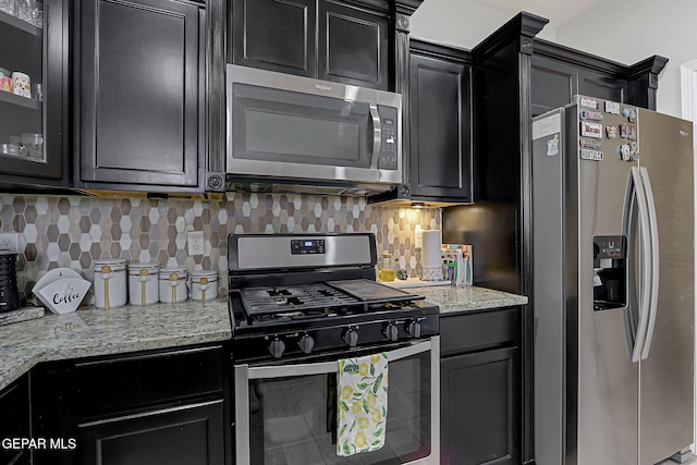 13120 Wesleyan, El Paso, TX 79928 - kitchen featuring stainless steel appliances, dark cabinetry, decorative backsplash, and light stone counters