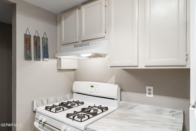 5823 Chippendale Ave, El Paso, TX 79934 - kitchen with white range with gas cooktop, under cabinet range hood, light countertops, a textured wall, and white cabinets