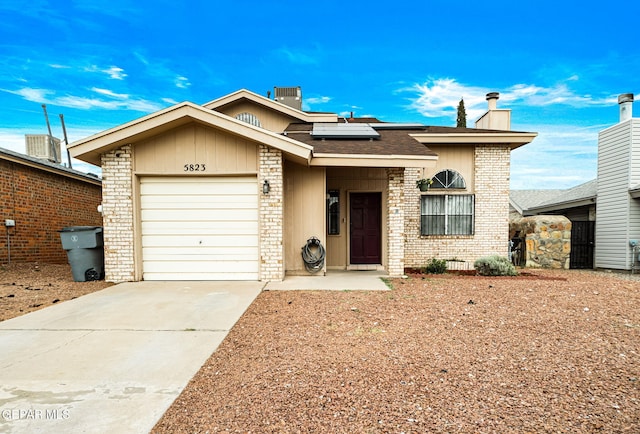 5823 Chippendale Ave, El Paso, TX 79934 - view of front of property with driveway, roof mounted solar panels, a chimney, a garage, and brick siding