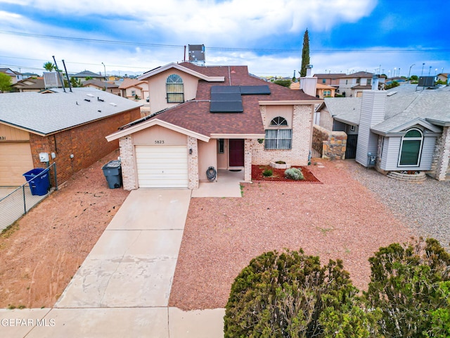 5823 Chippendale Ave, El Paso, TX 79934 - view of front of home with roof with shingles, brick siding, concrete driveway, roof mounted solar panels, and a residential view