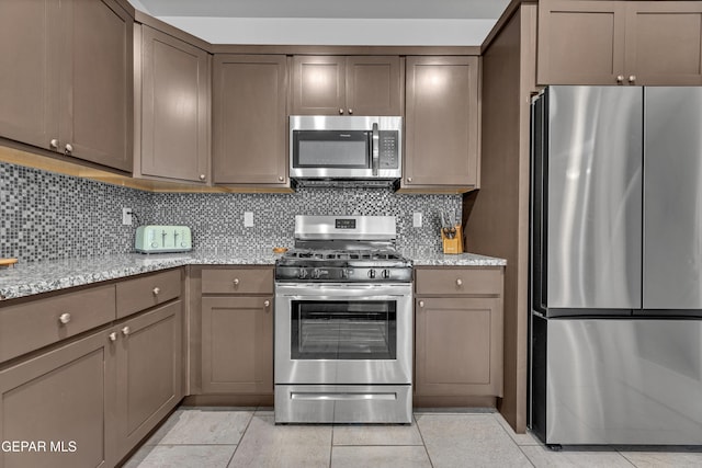 203 Bretby Pl, El Paso, TX 79928 - kitchen with stainless steel appliances, decorative backsplash, light tile patterned flooring, and light stone countertops