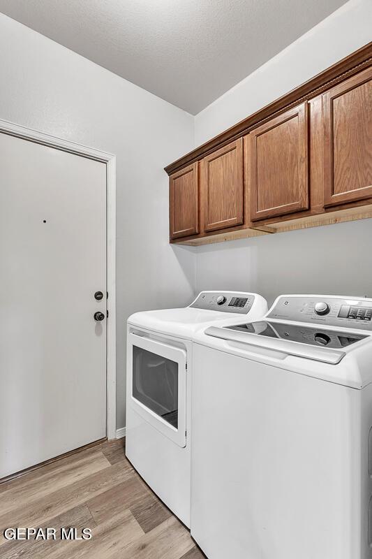 12879 Hidden Grove Dr, El Paso, TX 79938 - laundry room with washing machine and dryer, cabinet space, and light wood-style flooring