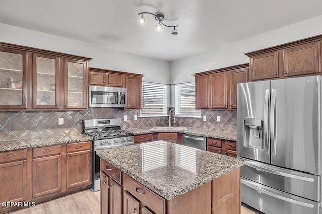 12879 Hidden Grove Dr, El Paso, TX 79938 - kitchen featuring appliances with stainless steel finishes, light stone counters, tasteful backsplash, and a center island