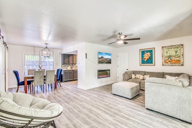 350 Thunderbird Dr Unit 59, El Paso, TX 79912 - living room featuring a chandelier, light wood-type flooring, a ceiling fan, and a glass covered fireplace