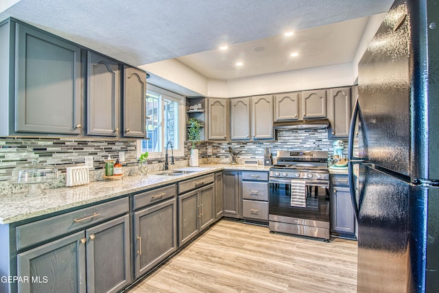 350 Thunderbird Dr Unit 59, El Paso, TX 79912 - kitchen with freestanding refrigerator, stainless steel range, a textured ceiling, light wood-type flooring, and backsplash
