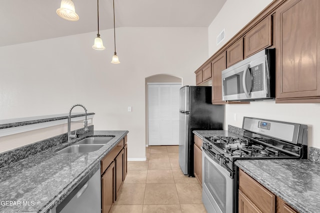14197 Ranier Point Dr, El Paso, TX 79938 - kitchen with stainless steel appliances, dark stone counters, arched walkways, light tile patterned floors, and decorative light fixtures