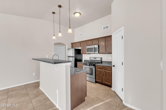 14197 Ranier Point Dr, El Paso, TX 79938 - kitchen with stainless steel appliances, a high ceiling, light tile patterned flooring, a kitchen breakfast bar, and dark stone counters