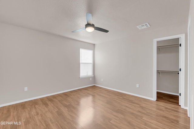 14197 Ranier Point Dr, El Paso, TX 79938 - unfurnished bedroom with a walk in closet, light wood-style floors, a closet, and ceiling fan