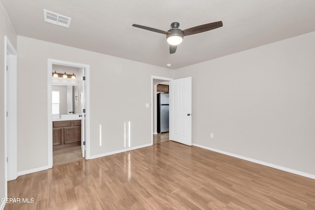 14197 Ranier Point Dr, El Paso, TX 79938 - unfurnished bedroom with freestanding refrigerator, light wood-type flooring, ensuite bathroom, and a ceiling fan