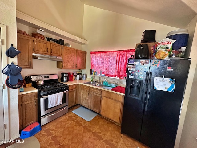 800 Derrickson Dr, El Paso, TX 79912 - kitchen with stainless steel gas range oven, black fridge with ice dispenser, under cabinet range hood, light countertops, and brown cabinets