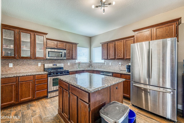 401 Everlook Ln, Horizon City, TX 79928 - kitchen featuring appliances with stainless steel finishes, backsplash, a kitchen island, glass insert cabinets, and stone countertops