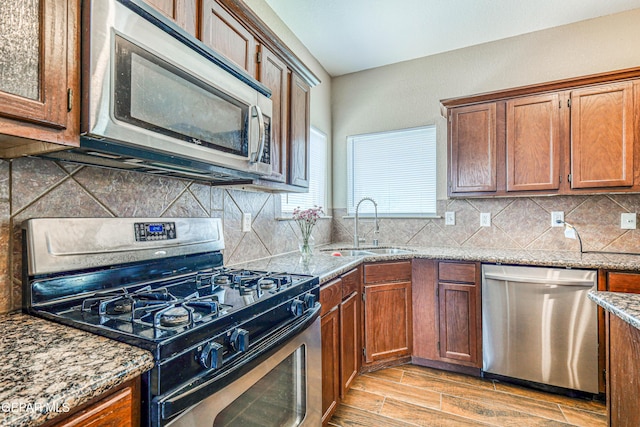 401 Everlook Ln, Horizon City, TX 79928 - kitchen featuring appliances with stainless steel finishes, light stone countertops, light wood-style flooring, and decorative backsplash