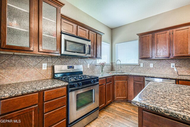 401 Everlook Ln, Horizon City, TX 79928 - kitchen featuring stainless steel appliances, light wood-style floors, decorative backsplash, and dark stone counters