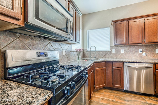 401 Everlook Ln, Horizon City, TX 79928 - kitchen with appliances with stainless steel finishes, light stone counters, decorative backsplash, and wood finished floors